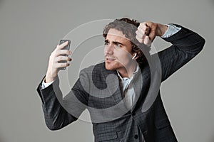 Cheerful man in earphone making fun while taking selfie on cellphone