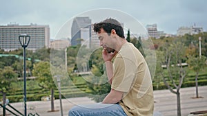 Cheerful man ending call at city park bench closeup. Smiling spanish guy hung up