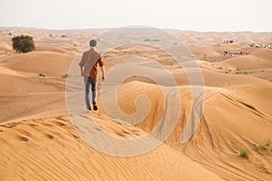 A cheerful man enjoys a beautiful sunset on a hill in the desert. Happy summer holidays. An active lifestyle.