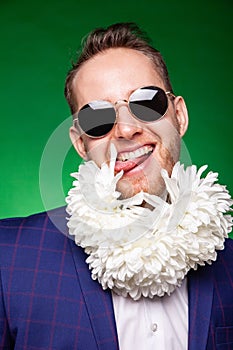 Cheerful man with flowers on neck and in suit in studio