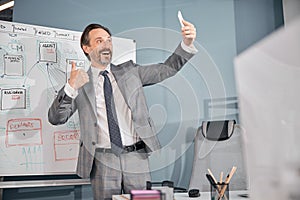 Cheerful man giving thumbs up and making selfie at work