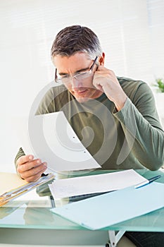 Cheerful man with glasses reading paper