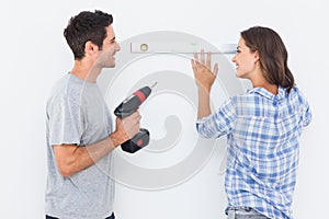 Cheerful man and his wife doing home improvements together