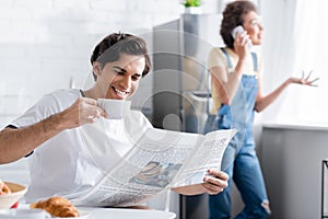 cheerful man holding cup and reading