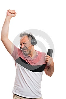 Cheerful man holding phone listening music in headphones dancing