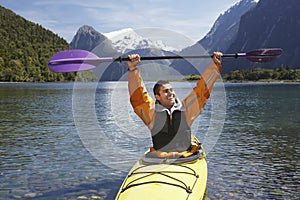 Cheerful Man Holding Up Oar In Mountain Lake