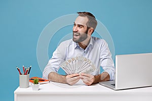 Cheerful man in light shirt work at desk with pc laptop isolated on blue background. Achievement business career concept