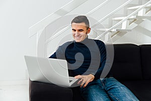 Cheerful man looking at laptop screen, at home