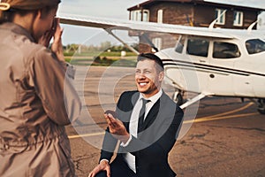 Cheerful man making proposal to his girlfriend at airdrome