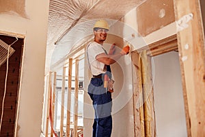 Cheerful man painting wall in house under construction