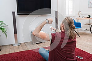 cheerful man with remote control gesturing and watching tv