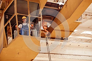 Cheerful man sitting in operator cabin of overhead crane