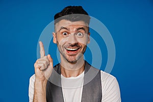 Cheerful man smiling and pointing upwards isolated over blue background