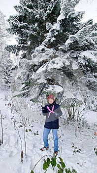 a cheerful man with a snowmaker and a snowball by a spruce tree in the snow.