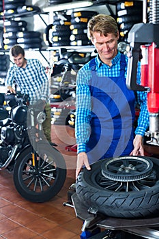 Cheerful man standing with motorcycle wheel