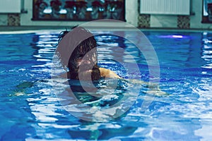 Cheerful man swims in pool on blue water background