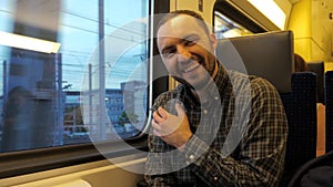 Cheerful man telling a joke and laughing in a train.