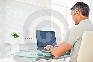Cheerful man using his laptop at desk