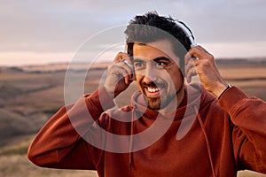 Cheerful Man Wearing Headphones Before Training In Mountains, Motivated, Smiling