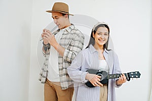 Cheerful man and woman playing thier instruments inside a room.