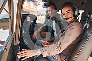 Cheerful man and woman sitting inside plane cockpit