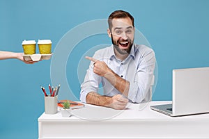 Cheerful man work at desk with pc laptop isolated on blue background. Food products delivery courier service from shop