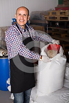 Cheerful man worker holding gunnysack with malt