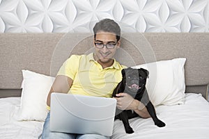 Cheerful man works on laptop and hugs his cute pet