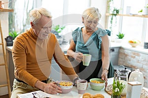 Cheerful married couple preparing to eat cereals for breakfast