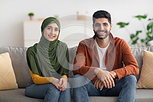 Cheerful Married Middle Eastern Couple Sitting On Sofa At Home
