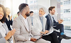 Cheerful mature caucasian businesswoman laughing with a colleague during a presentation in an office. Woman in audience