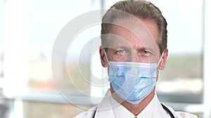 Cheerful mature male doctor in protective mask.