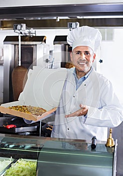 Cheerful mature man cook giving freshly made pizza
