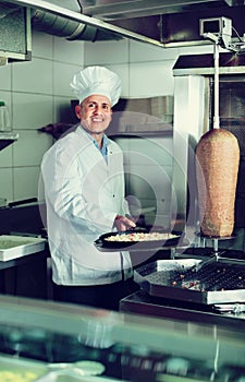 Cheerful mature man cook making pizza in pan on kitchen