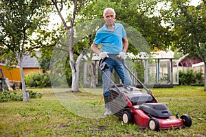 Cheerful mature man with lawnmower on a farm