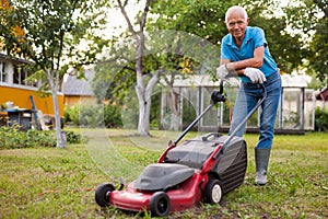 Cheerful mature man with lawnmower on a farm