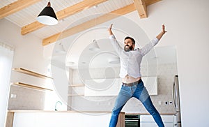 Cheerful mature man moving in new unfurnished house, jumping.