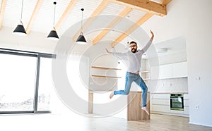 Cheerful mature man moving in new unfurnished house, jumping.