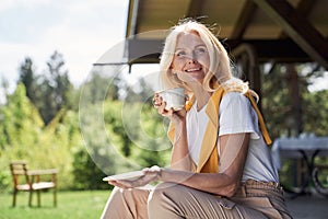 Cheerful mature woman enjoying hot drink outdoors