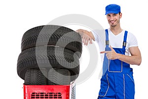 Cheerful mechanic pointing in new tires