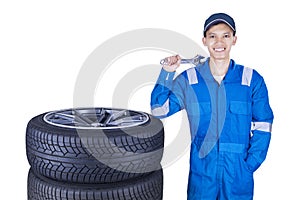 Cheerful mechanic with tires and wrench