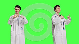 Cheerful medic doing thumbs up symbol against greenscreen backdrop