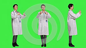 Cheerful medic doing thumbs up symbol against greenscreen backdrop