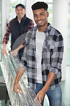 cheerful men carrying ladder