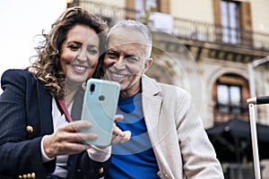 Cheerful mid adult couple having fun together taking a selfie in the street. Romantic senior couple smiling taking