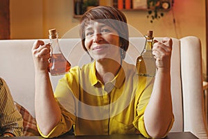 Cheerful mid adult woman with olive oil and balsamic vinegar bottles in italian cafe