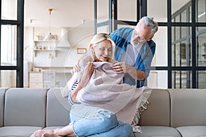 Cheerful mid age man wraps smiling woman in blanket