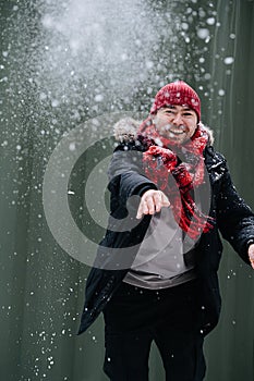 Cheerful middle age man in winter clothes throwing cloud of snow