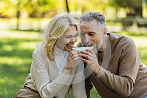 cheerful middle aged couple eating one