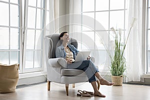 Cheerful middle aged woman using laptop at home